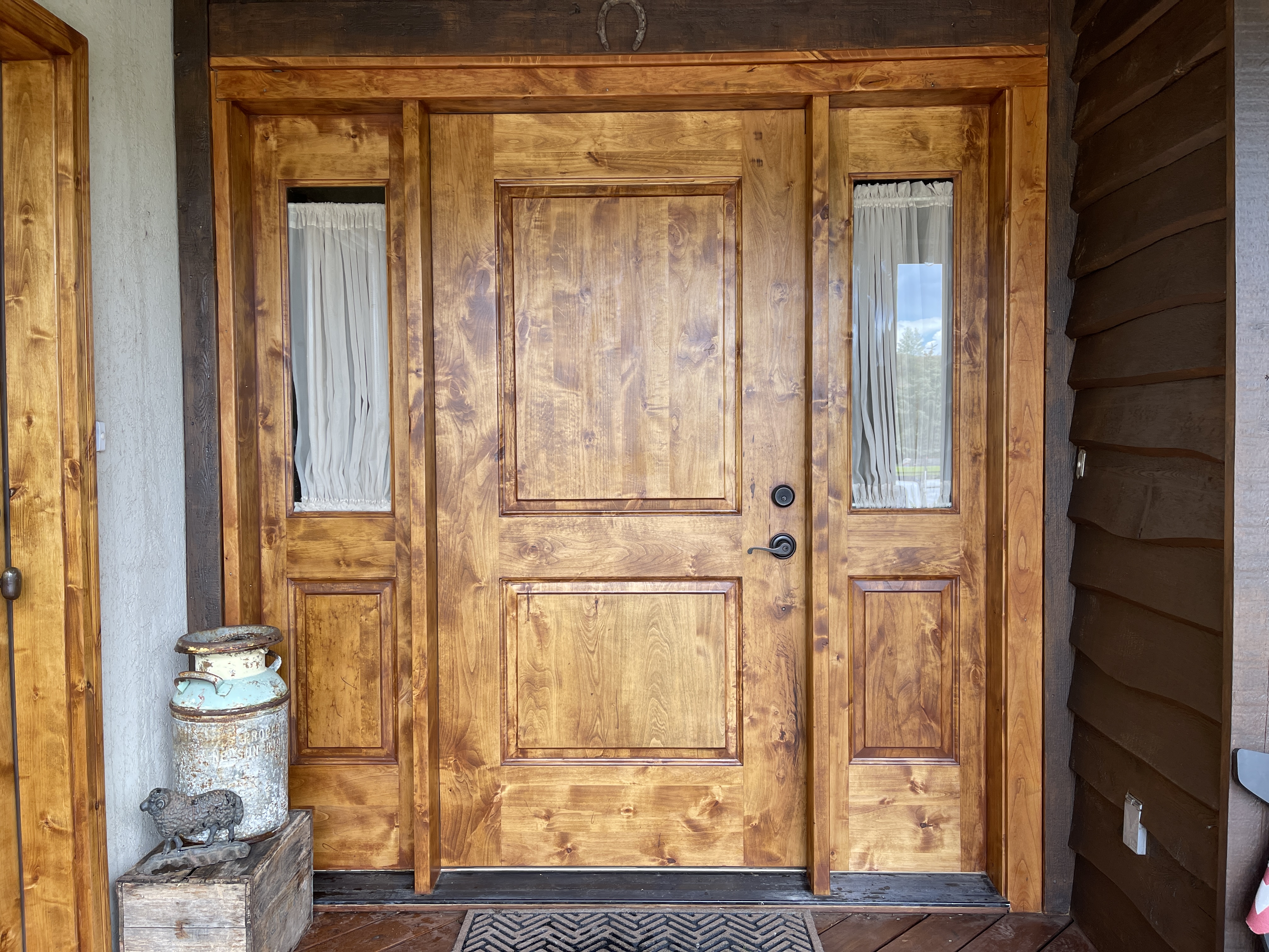 Beautiful knotty alder front door with warm stain in log cabin setting — door staining Utah