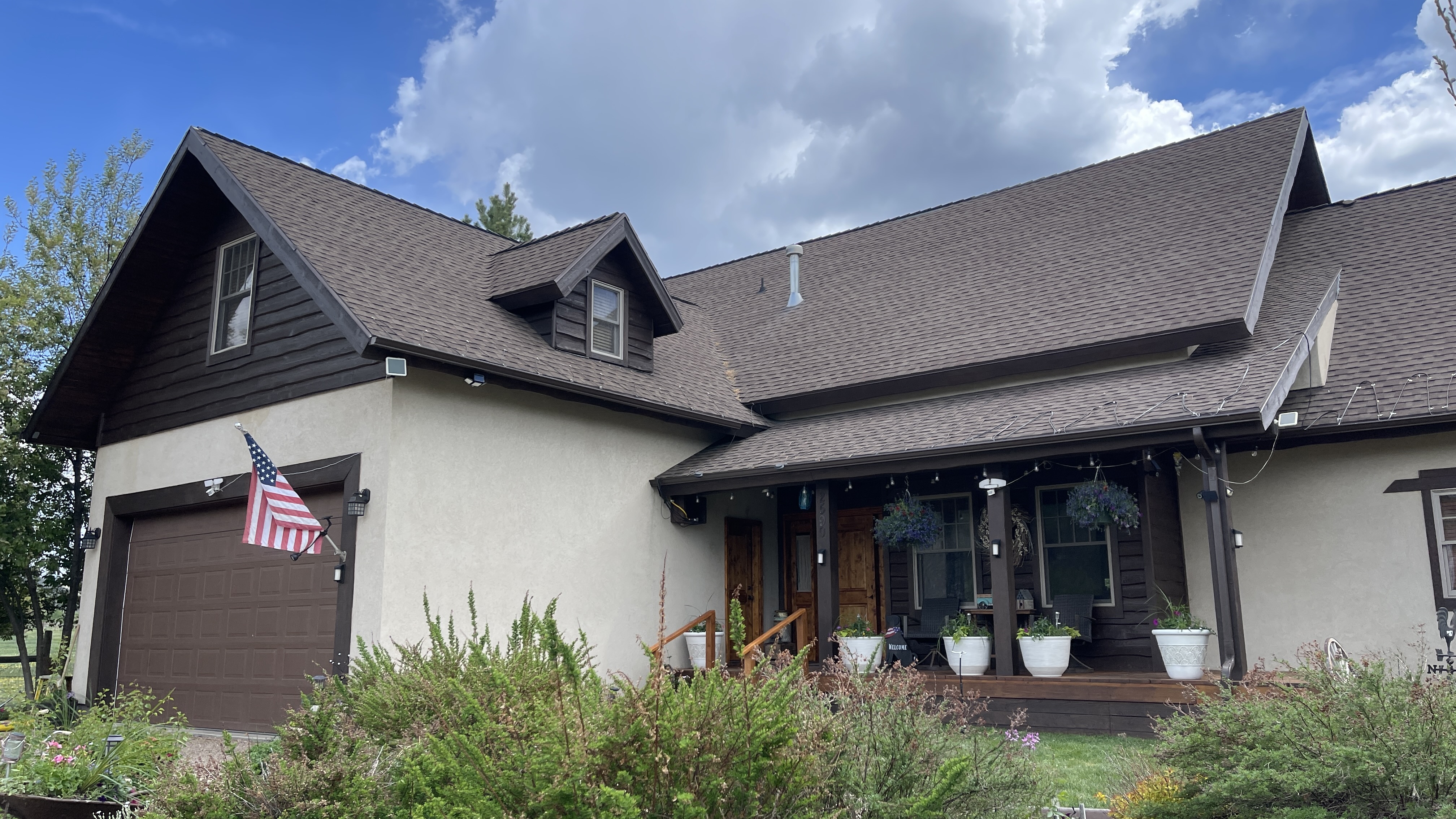 Home with stained wood porch, dark accents, and covered entry — exterior staining Utah