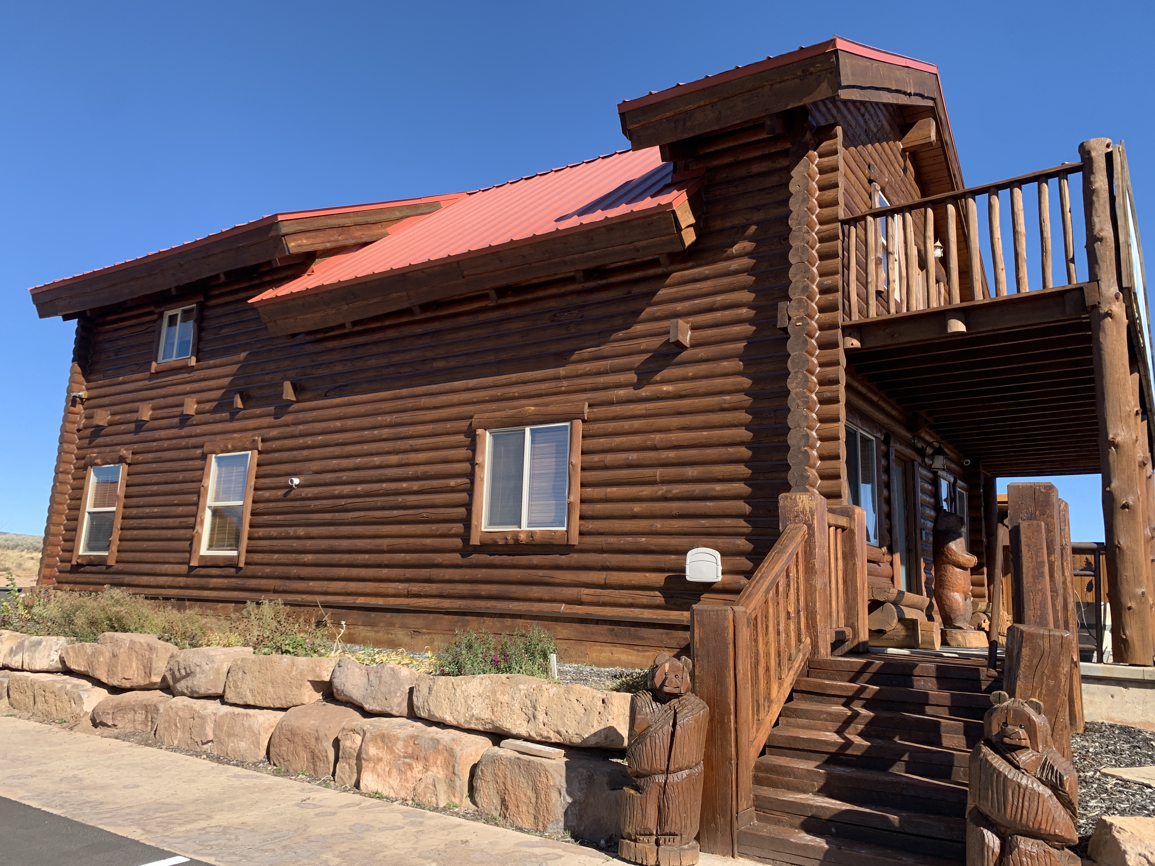 Freshly stained log cabin with warm brown tone and red metal roof — Summit County, Utah