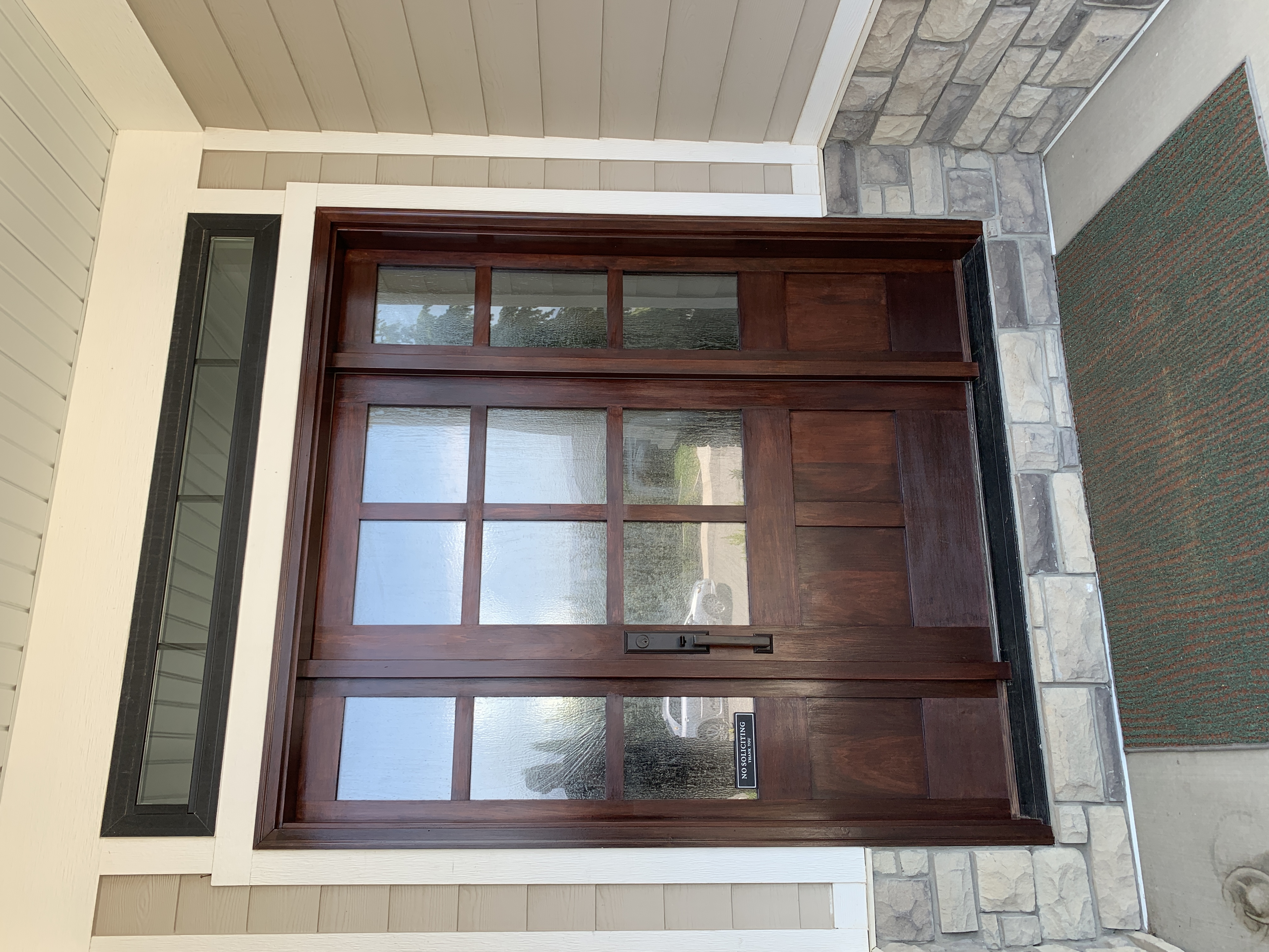 Rich mahogany stained front door with sidelights and stone base — exterior door staining Utah
