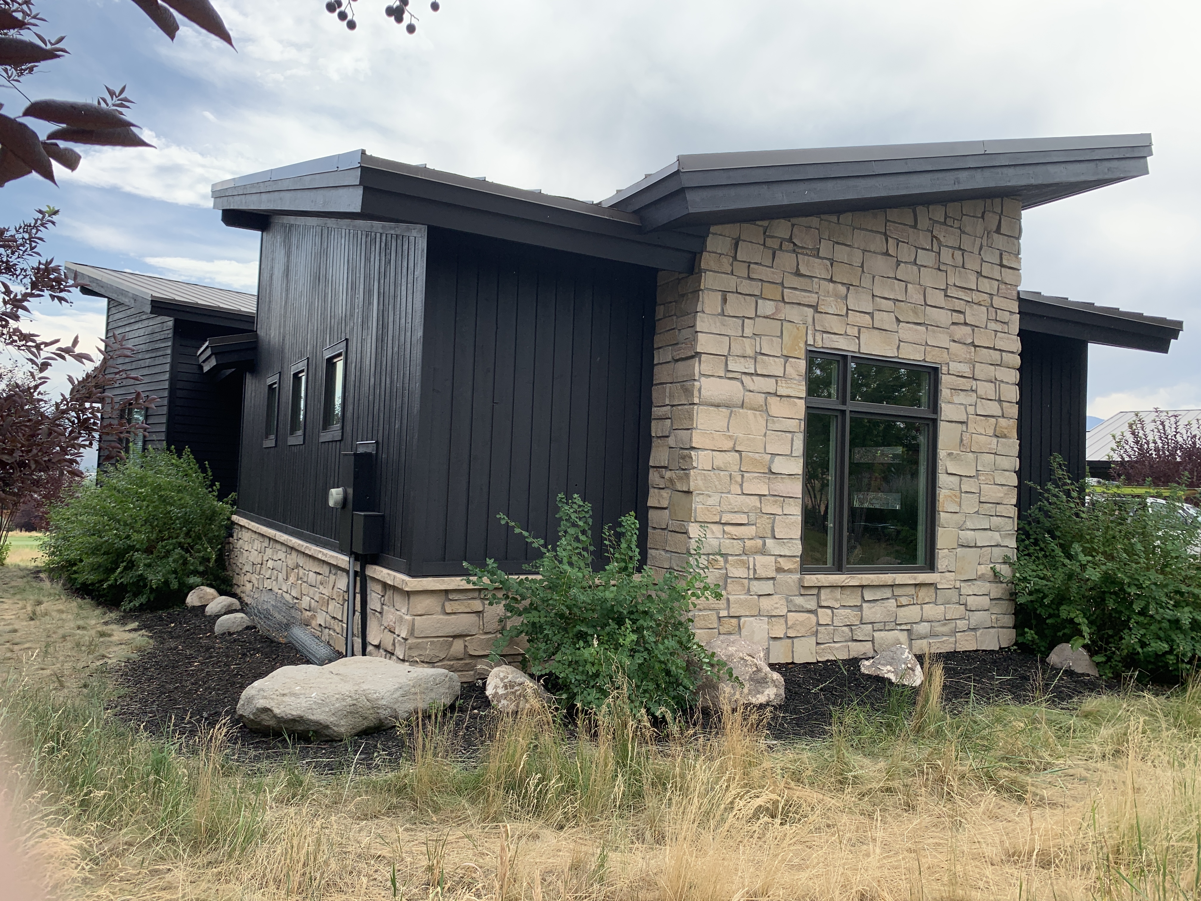 Modern home with dramatic black board-and-batten siding and sandstone — Summit County, Utah