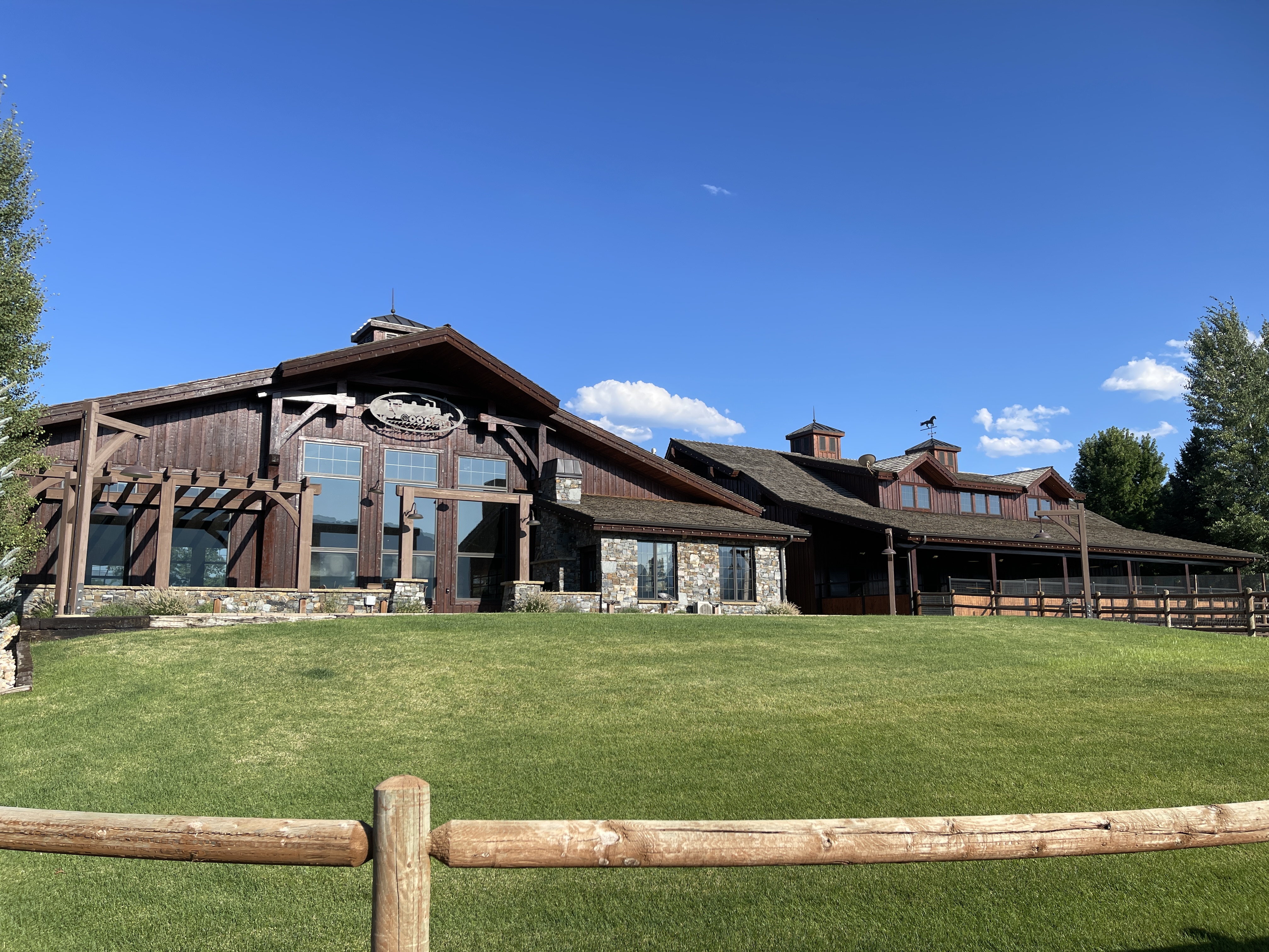 Large dark-stained ranch estate with stone accents and green lawn — Summit County, Utah
